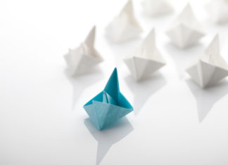 Ein blaues Schiff führt viele weiße Schiffe