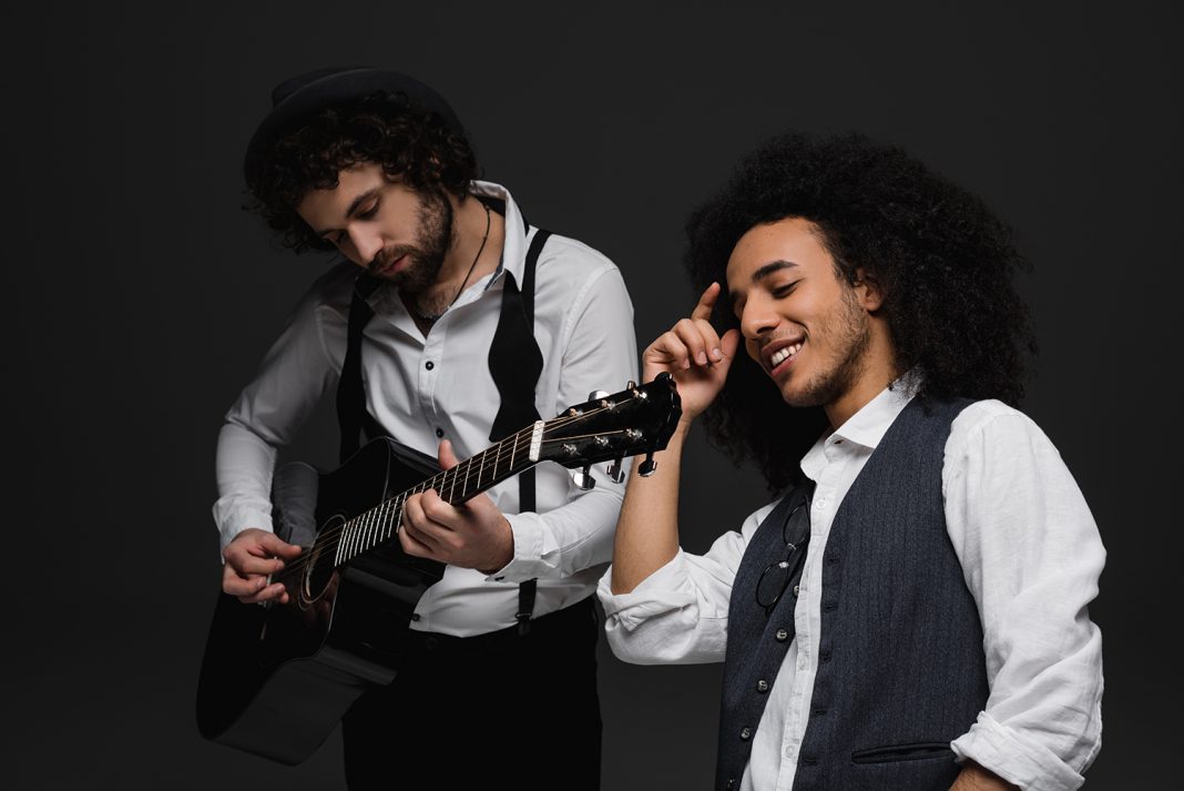 duet of musicians playing guitar and singing on black